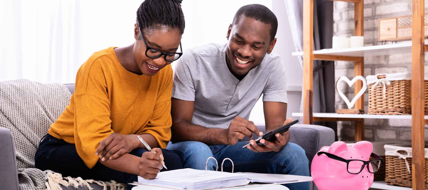 Young African Couple Sitting On Sofa Calculating Invoice