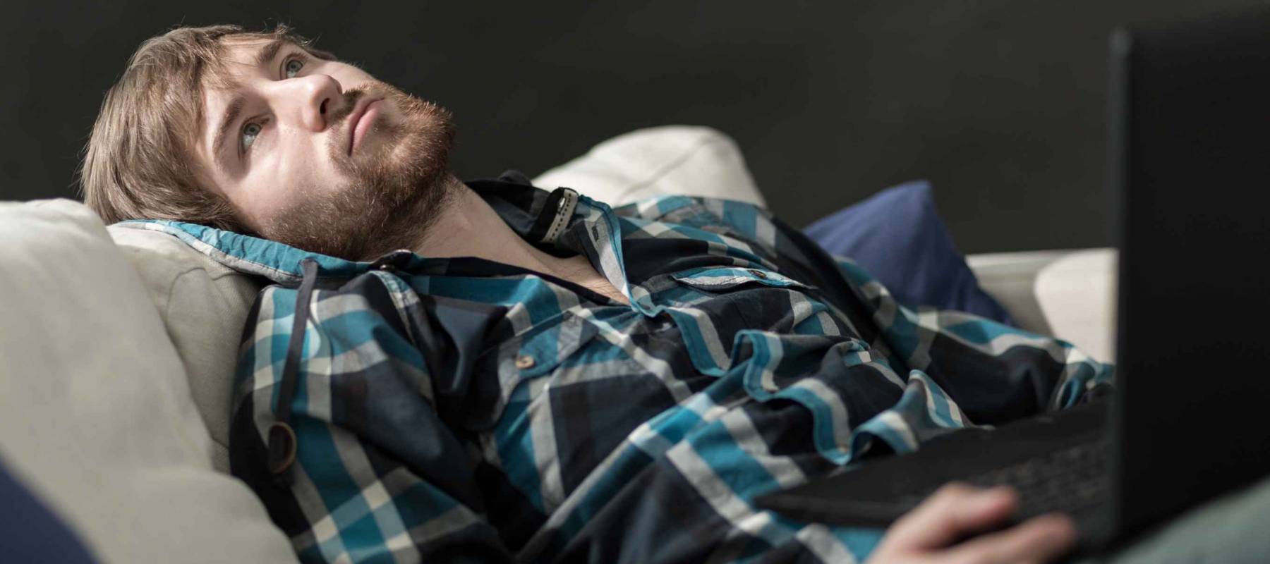 Bored man with a laptop on the couch