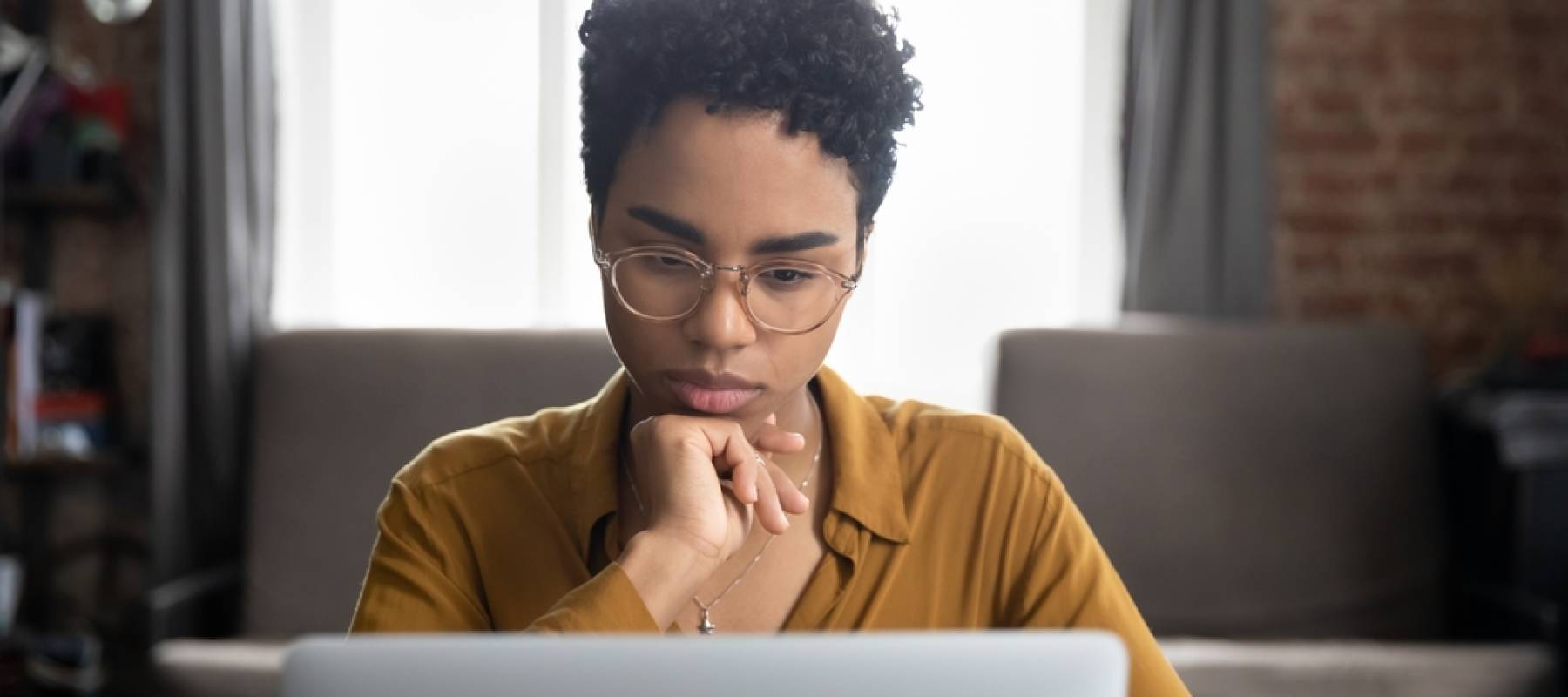 Pensive woman looking at laptop