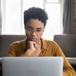 Pensive woman looking at laptop