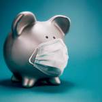 Close up of piggy bank, wearing protective face mask, isolated on blue background. Money saving concept in time of coronavirus pandemic.