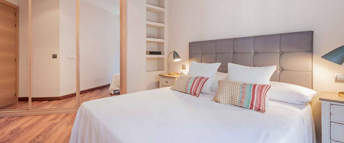 Double bedroom with three-section built-in wardrobe with mirrored doors in a vacation rental home