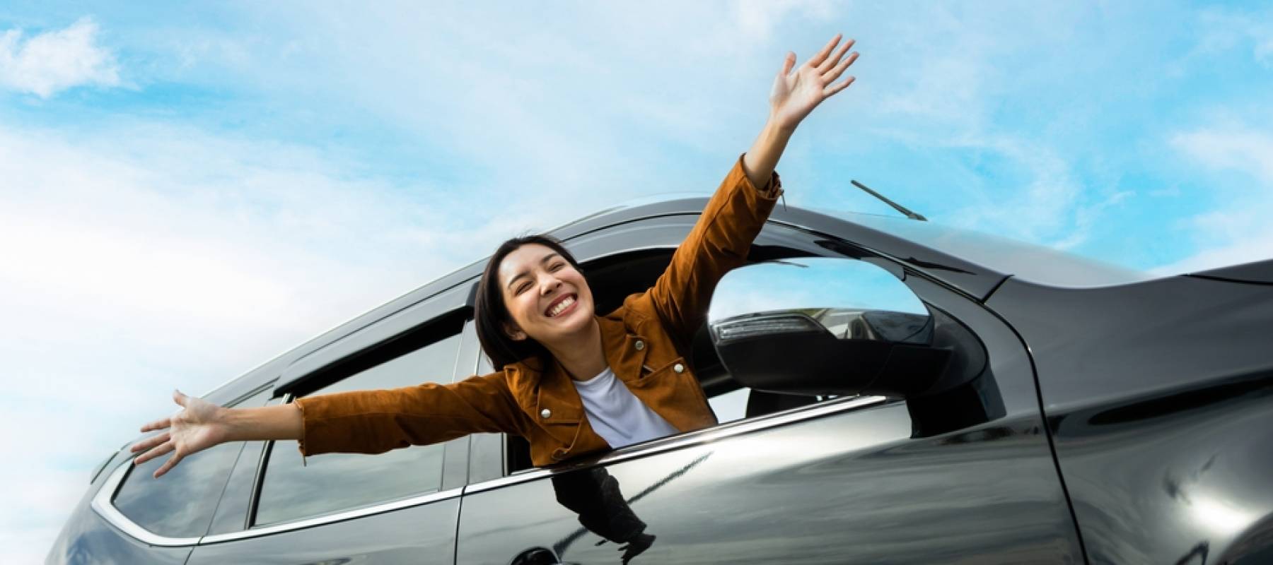 WOman hanging outside of car and is very happy