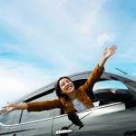 WOman hanging outside of car and is very happy