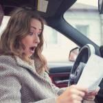 Young girl sitting inside of a car and reading fine papers, looking frustrated.