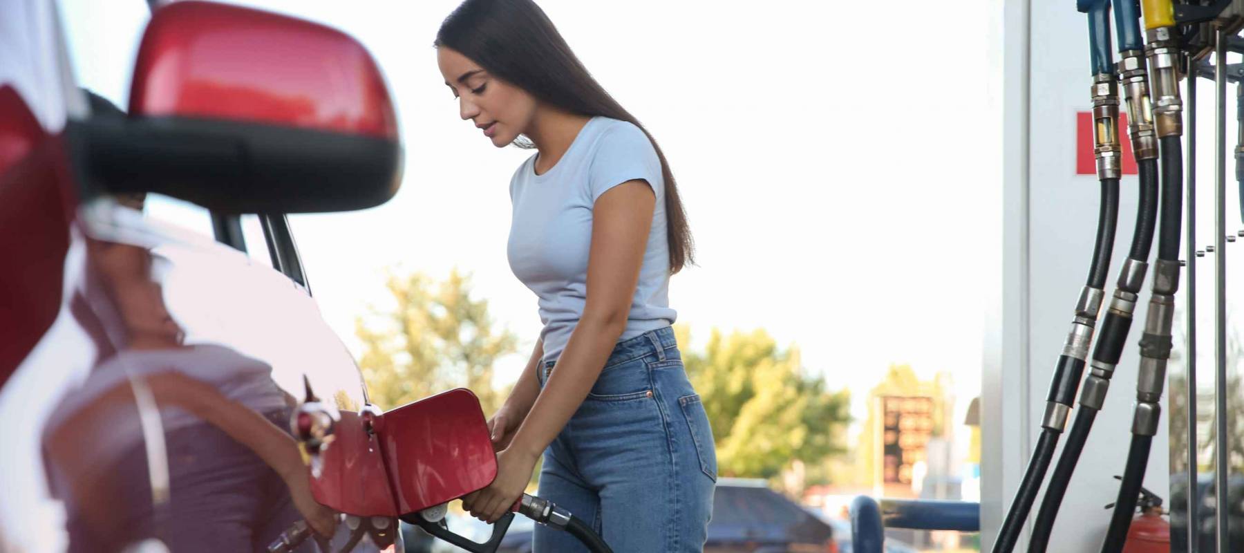 Young woman refueling car at self service gas station
