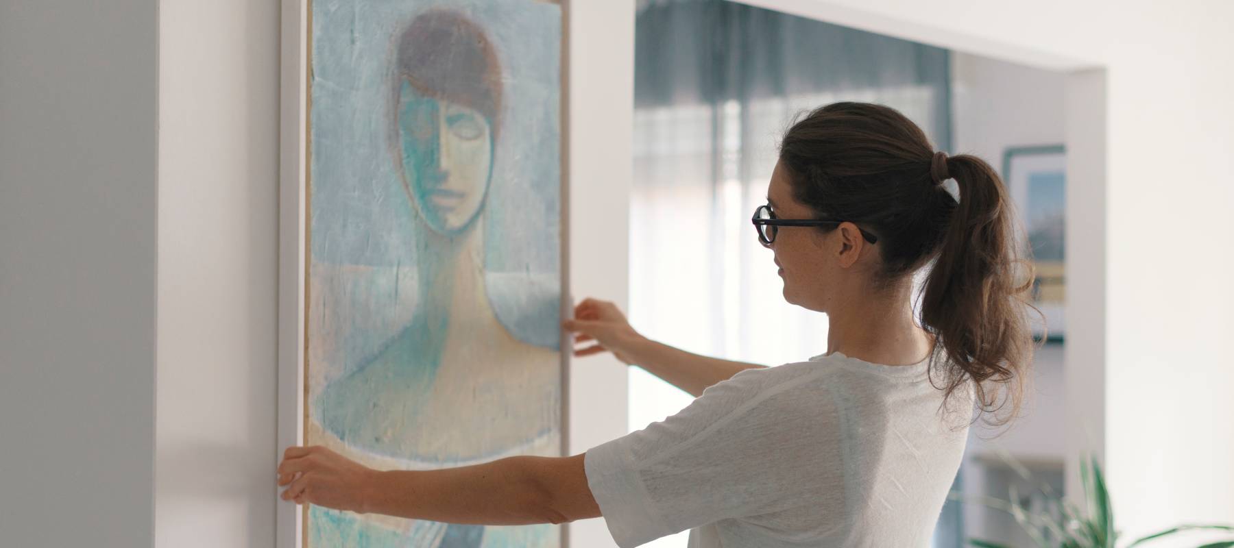 Woman putting up artwork in her home