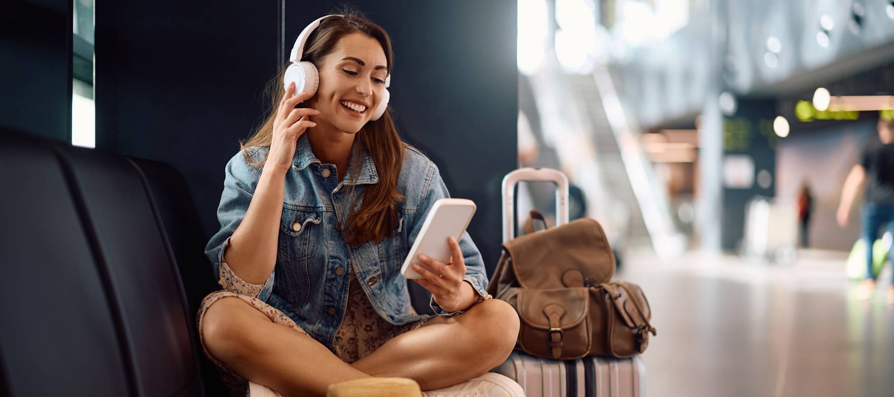 Young woman sitting in an airport happily talking to a friend on the phone