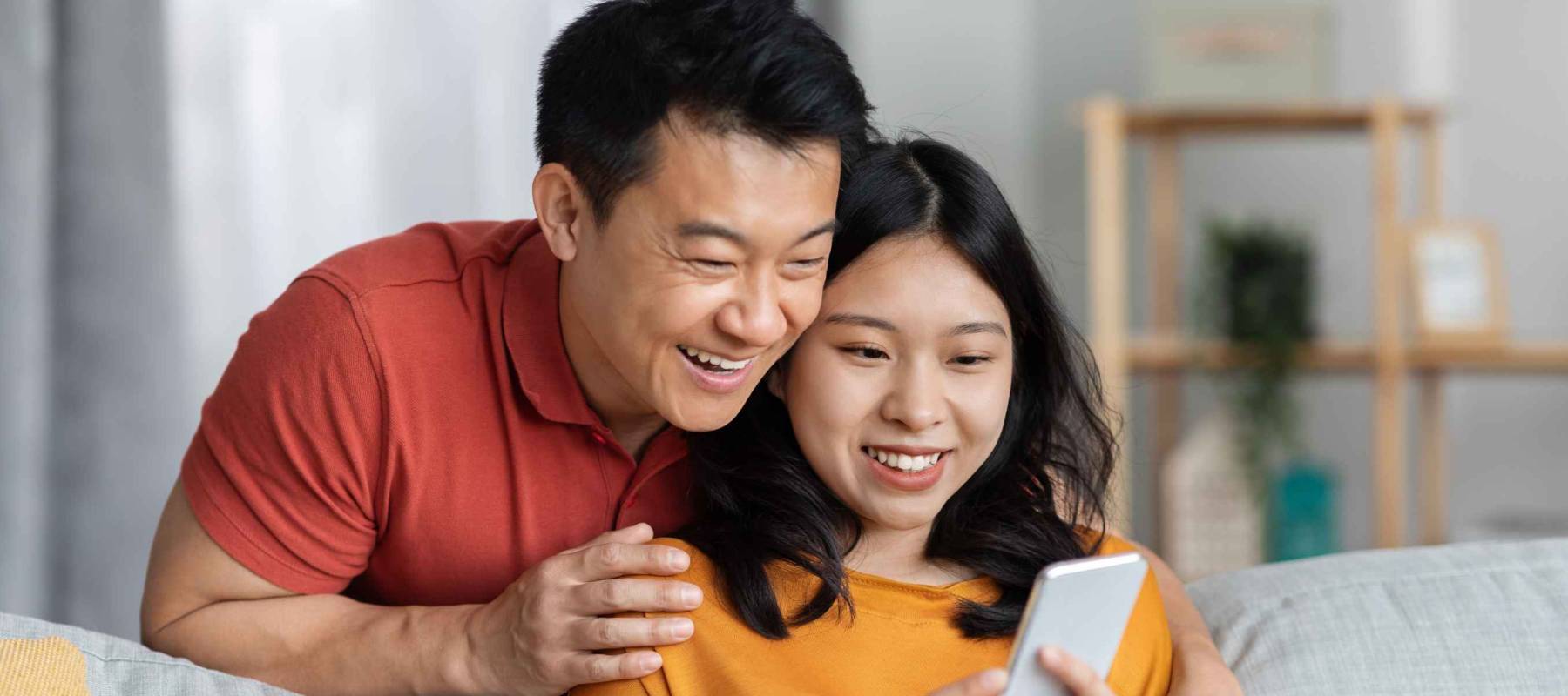 Happy asian lovers man and woman in casual sitting on couch