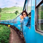 Woman traveler explores natural landscape via train, looking happy