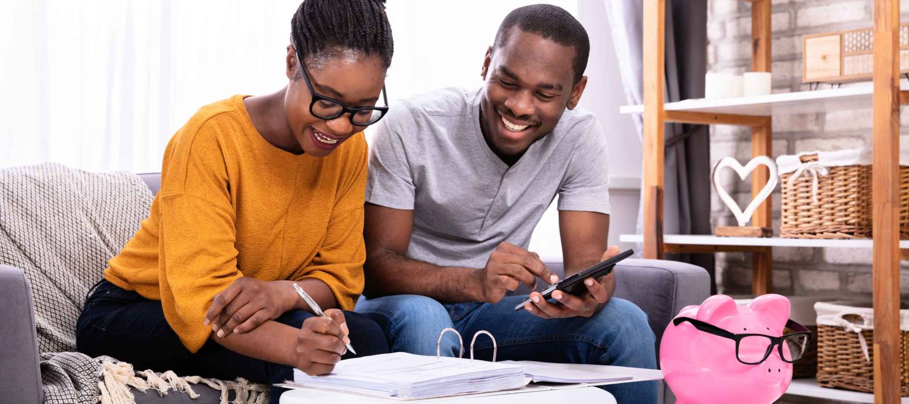 Young African Couple Sitting On Sofa Calculating Invoice