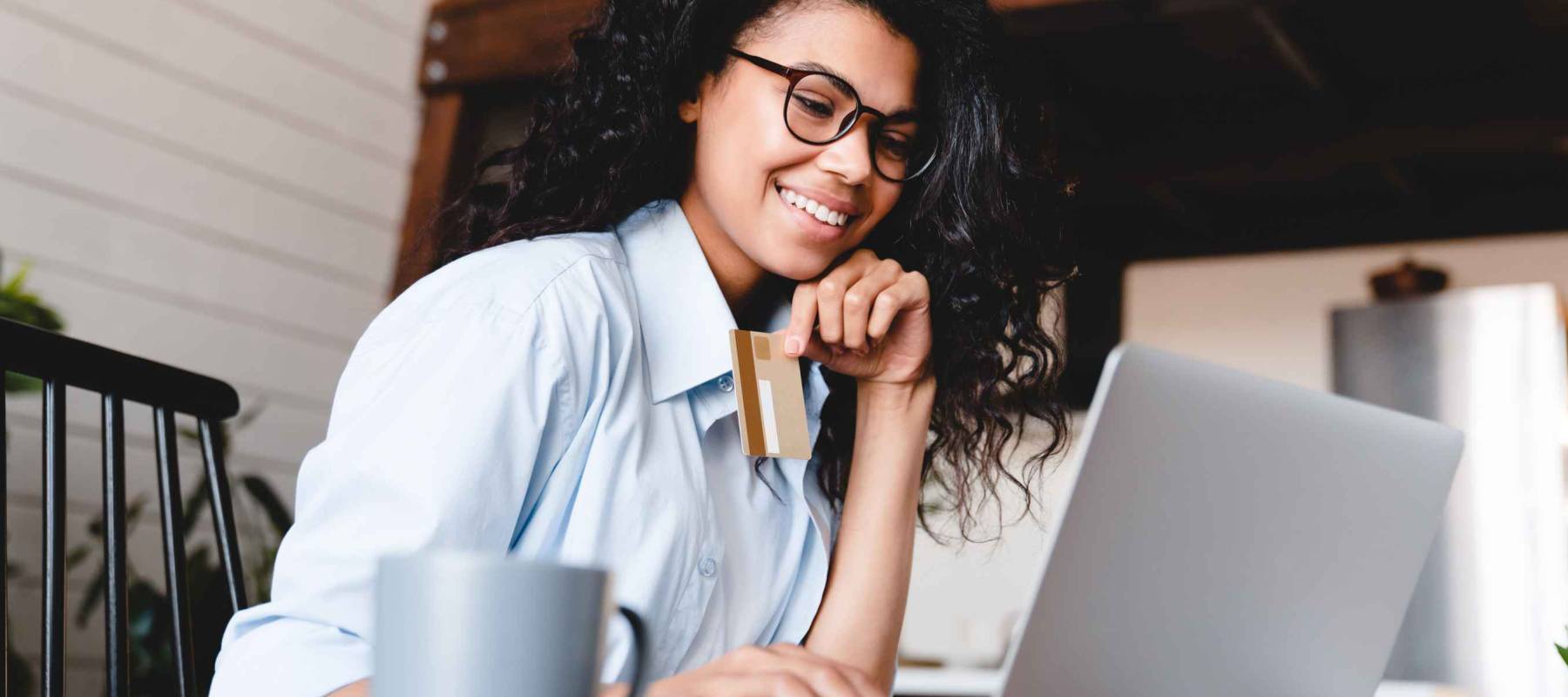 Beautiful young african-american woman buying online on laptop at home.