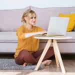 Attractive woman sitting on floor and sofa using laptop