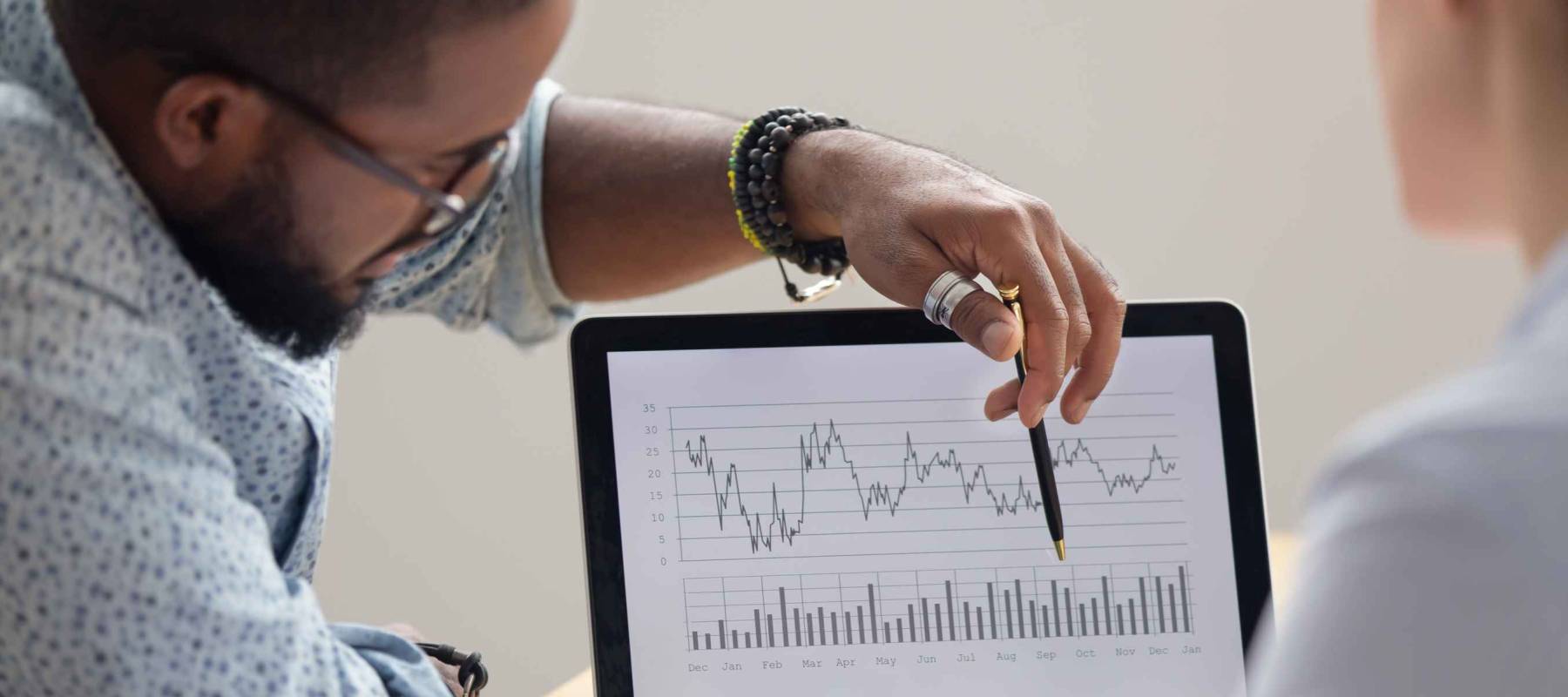 Focused african analyst showing client or colleague annual financial report analyzing business data on laptop screen