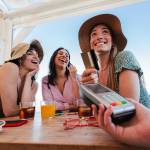 Happy young women paying for meal using debit card
