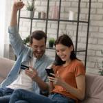 Happy young married family couple involved in online shopping, celebrating getting gift