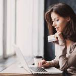 Young woman holding credit card and using laptop computer. Businesswoman working at home. Online shopping, e-commerce, internet banking, spending money, working from home concept