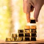 Man hand hold the gold bar with high value for invest and stack picked up put on the old wood on the morning sunlight in public park, Targeting of business to winner and success concept.