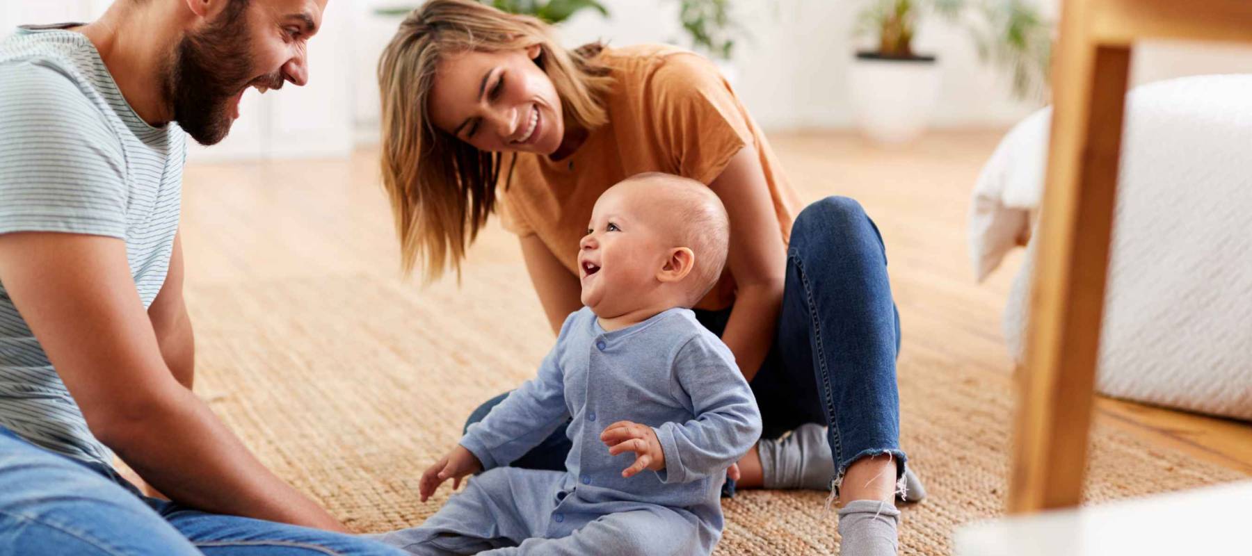 Parents Sitting On Floor At Home Playing With Baby Son
