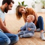 Parents Sitting On Floor At Home Playing With Baby Son