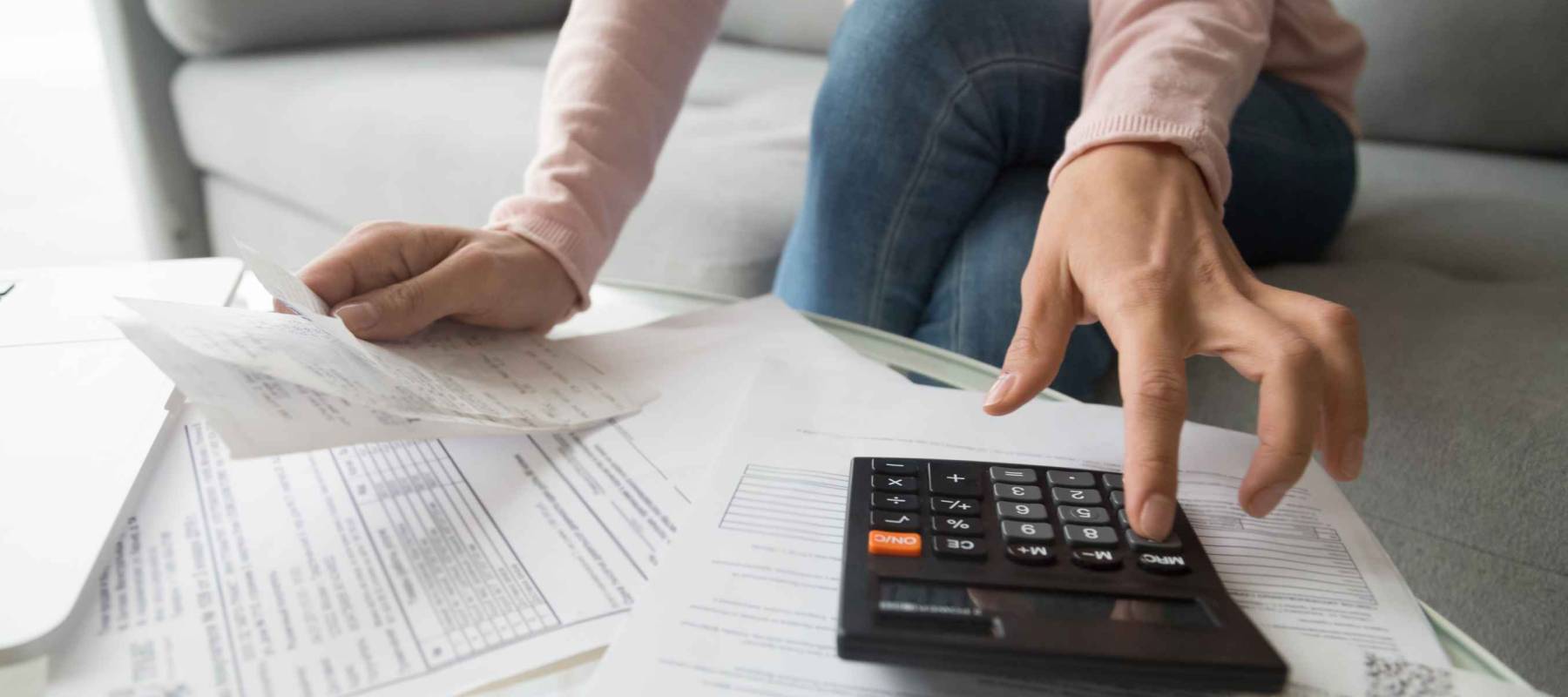 Woman renter holding paper bills using calculator for financial accounting