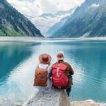 Travelers couple look at the mountain lake. Travel and active life concept with team. Adventure and travel in the mountains region in the Austria