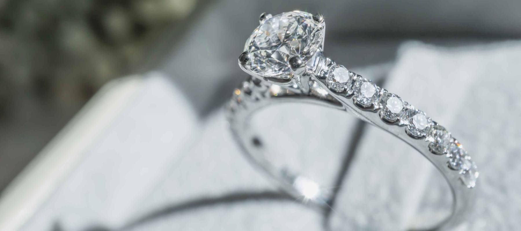 Close up of diamond ring with white flower, sunlight and shadow background. Love, valentine, relationship and wedding concept. Soft and selective focus.