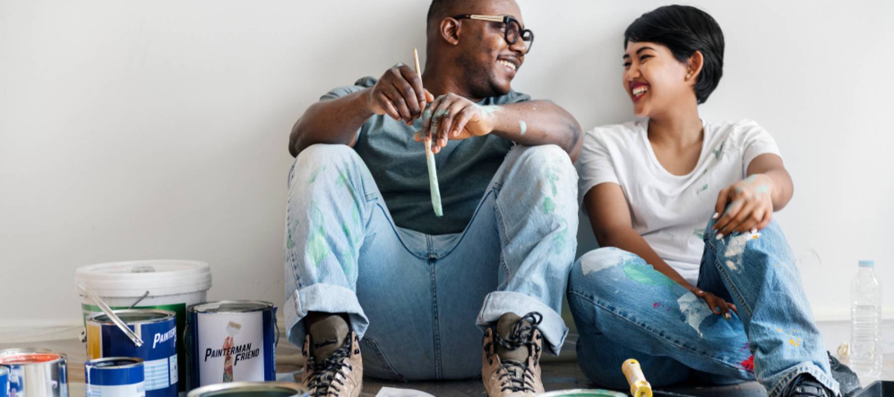 Couple painting house wall