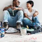 Couple painting house wall