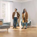 Happy and Excited Young Couple Look Around In Wonder at their Newly Purchased / Rented Apartment. Beautiful People Poses Happily. Big Bright Modern Home with Cardboard Boxes Ready to Unpack.