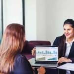 Investment consultant - Indian woman in formal suit, showing fund performance report with graphs on the laptop screen