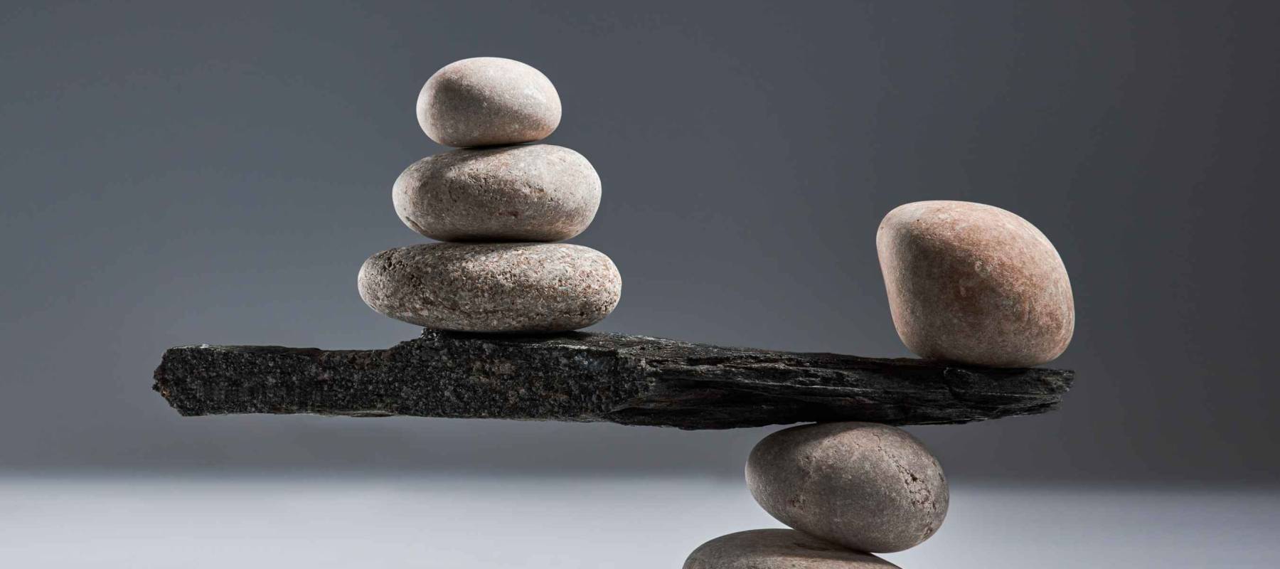 Balancing pyramid of sea pebbles on a gray background, the concept of harmony and balance, heavy and light. Stones in the form of scales with balancing stones.