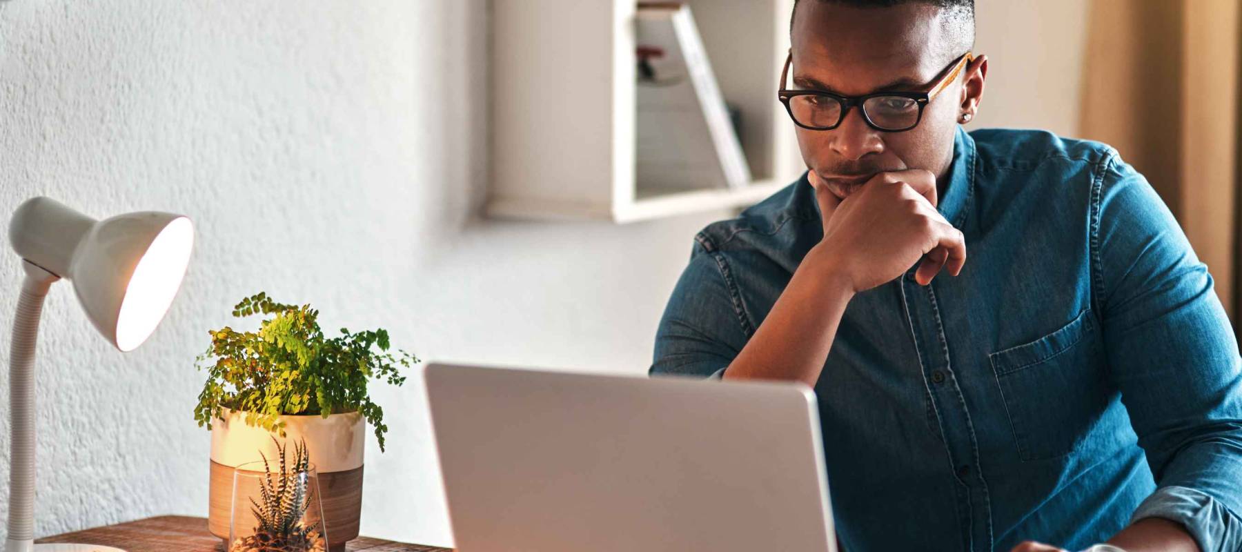 I wonder what I should do here. Cropped shot of a handsome young businessman sitting in his home office and looking contemplative while working on his laptop.