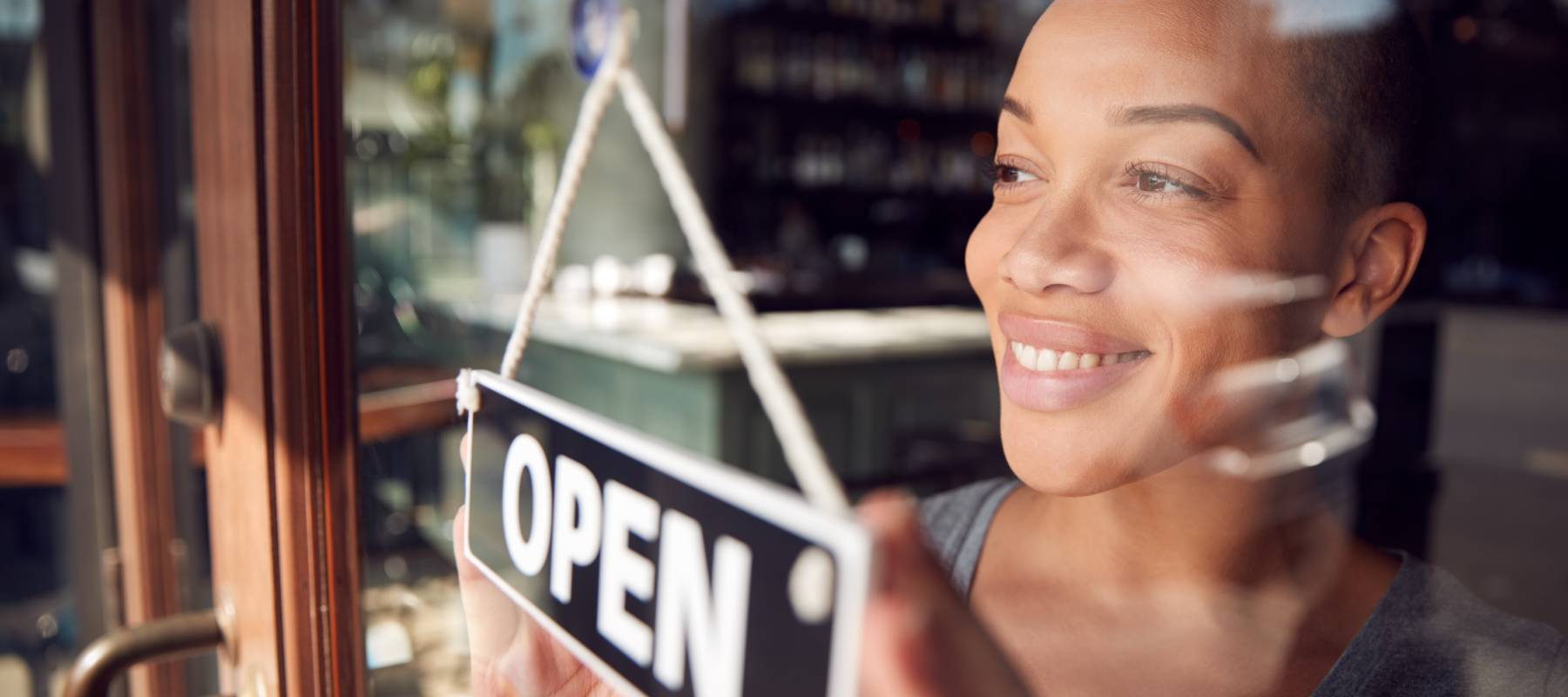 Woman stands in front of business entrance with open sign