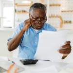 Older man looking surprised and concerned at documents