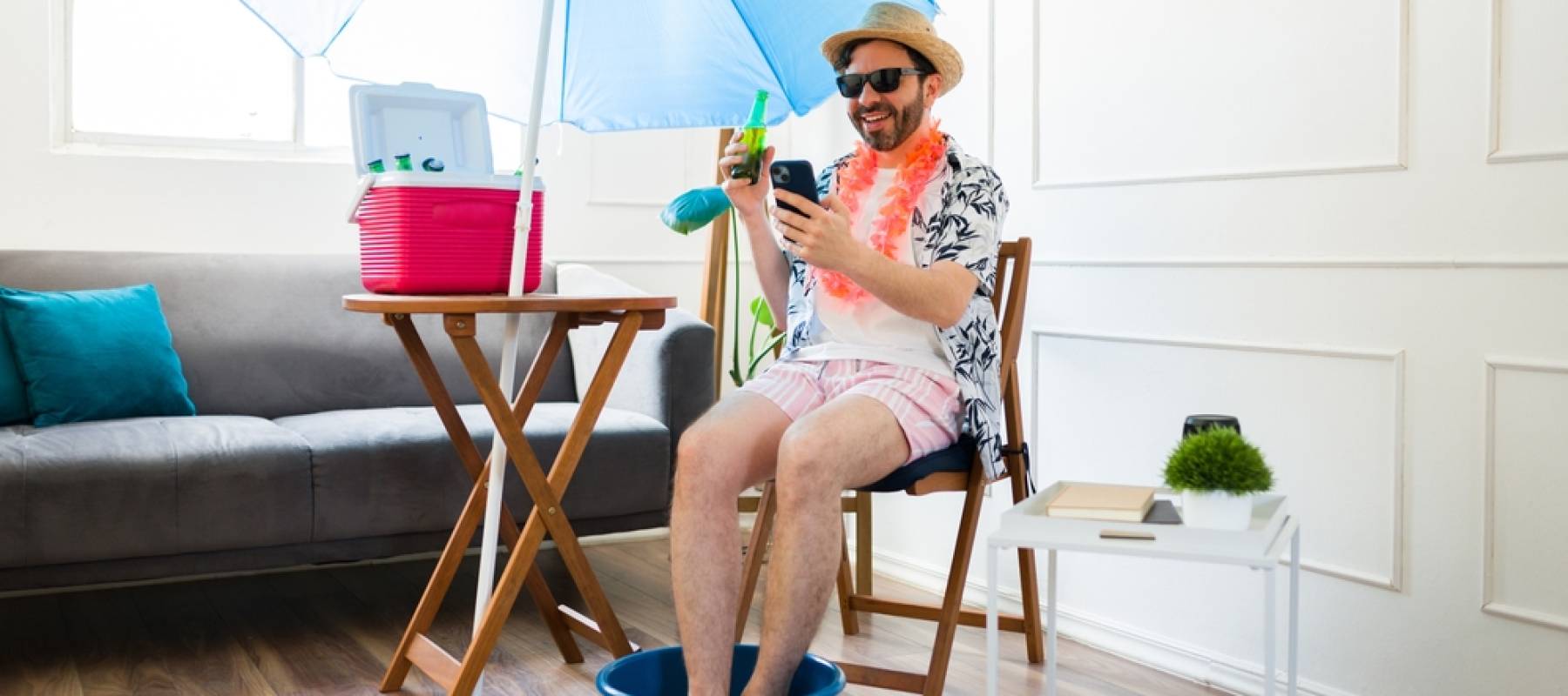 Excited man laughing at home having fun texting on the smartphone while having a pedicure pretending to be at the beach