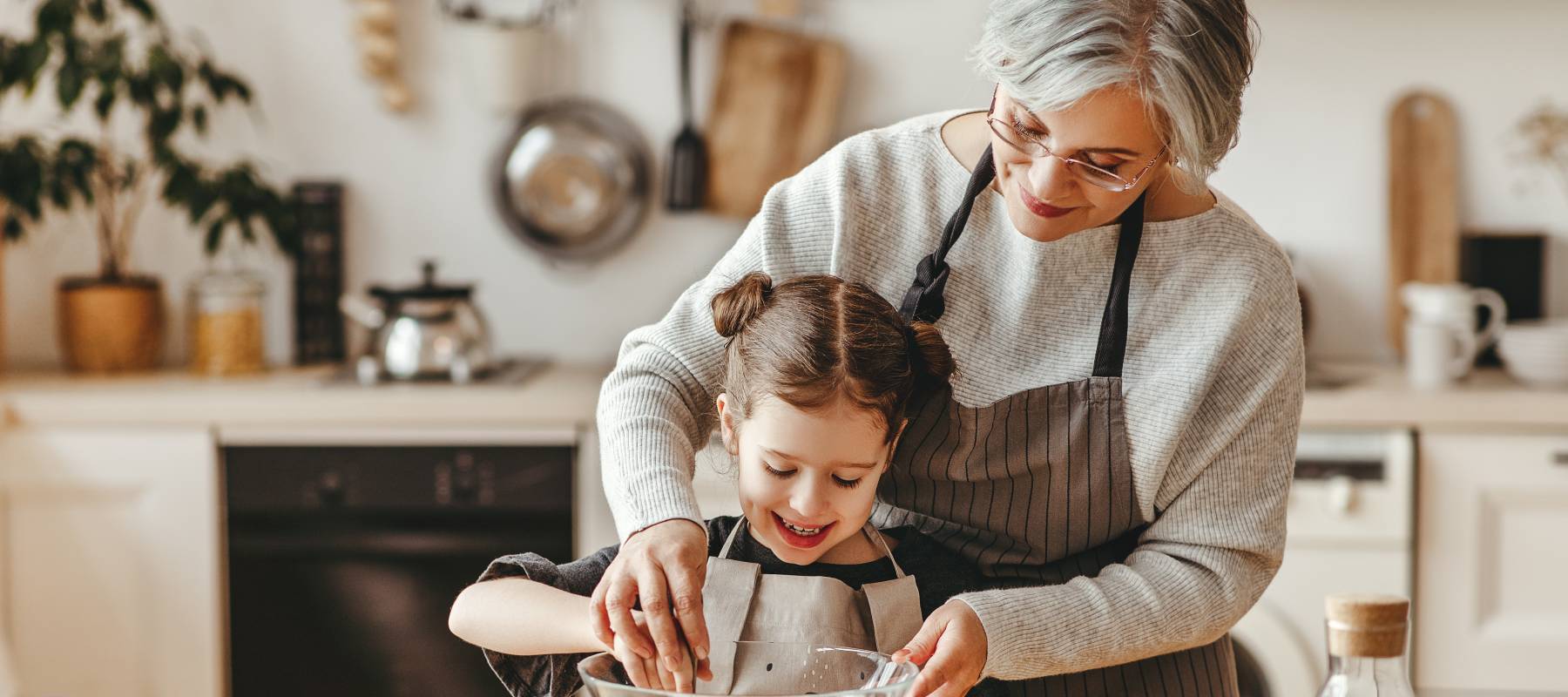 Happy grandmother helping child to bake
