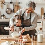 Happy grandmother helping child to bake