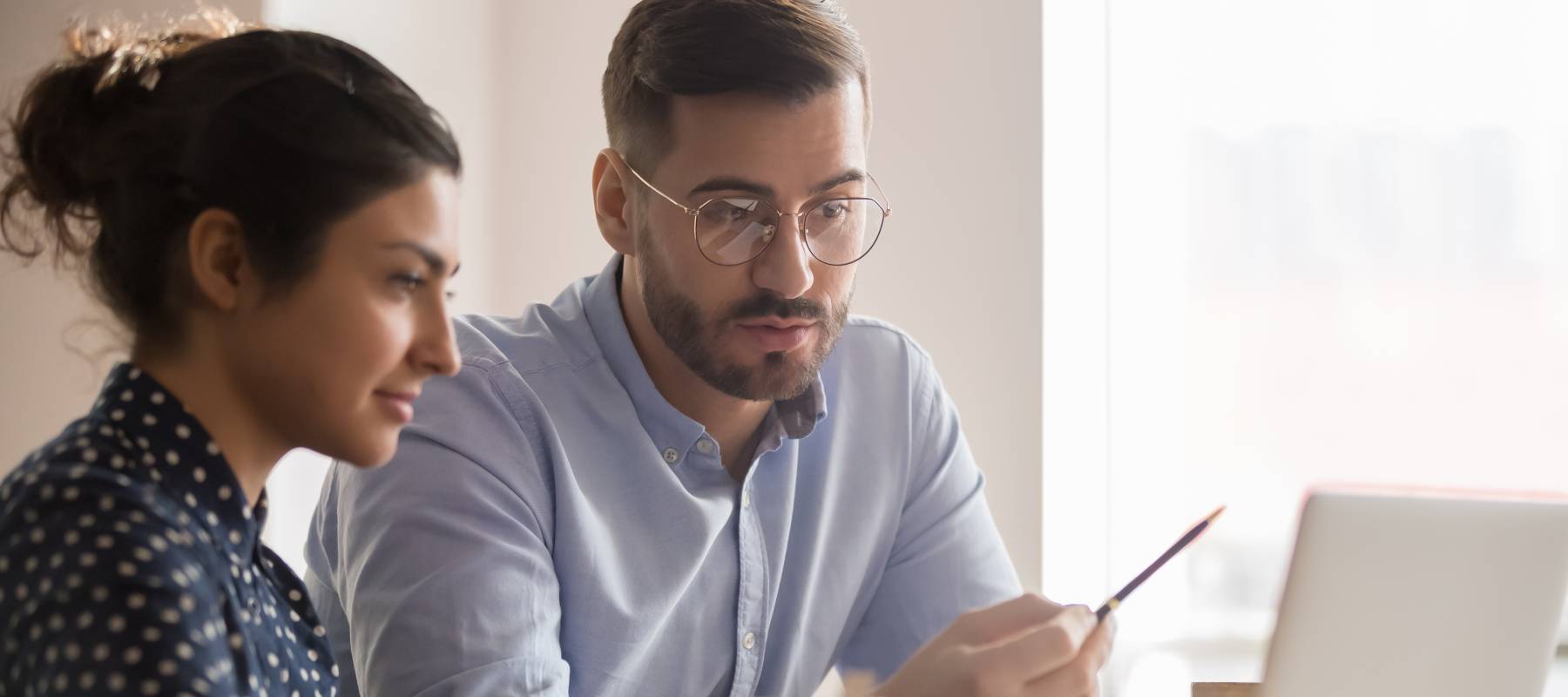 Businessman explaining something on computer screen to younger woman