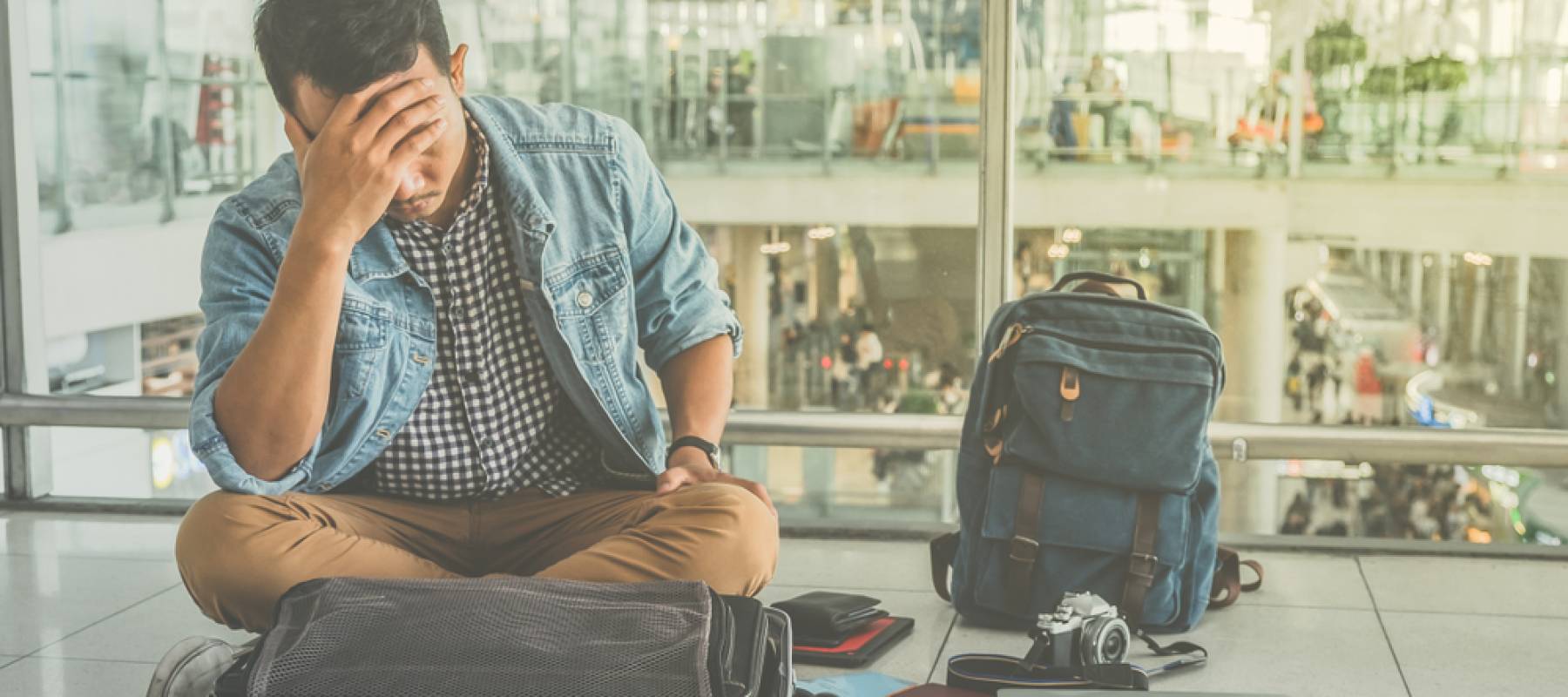 Young traveler sitting at the international airport, checking for lost items