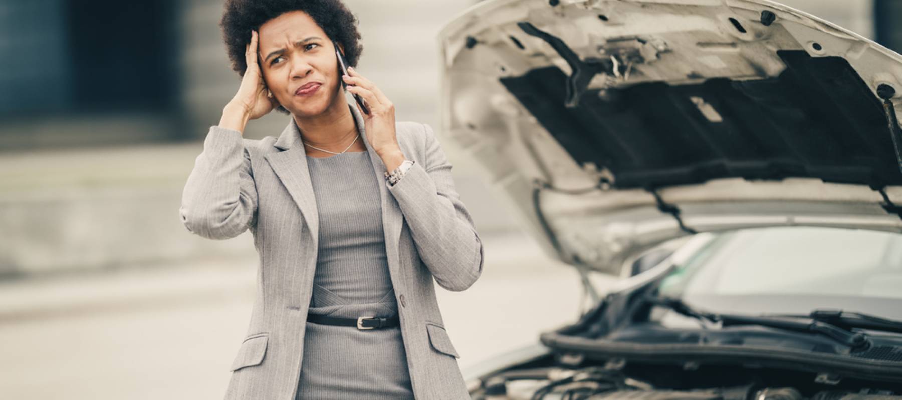 Stressed woman calling roadside assistance after her car broke down