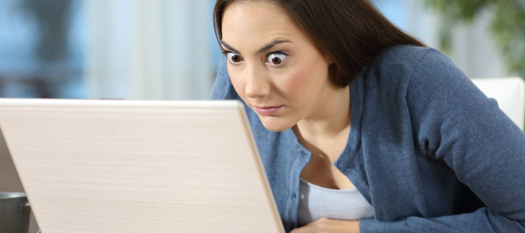 Perplexed woman reading on a laptop on a desk at home