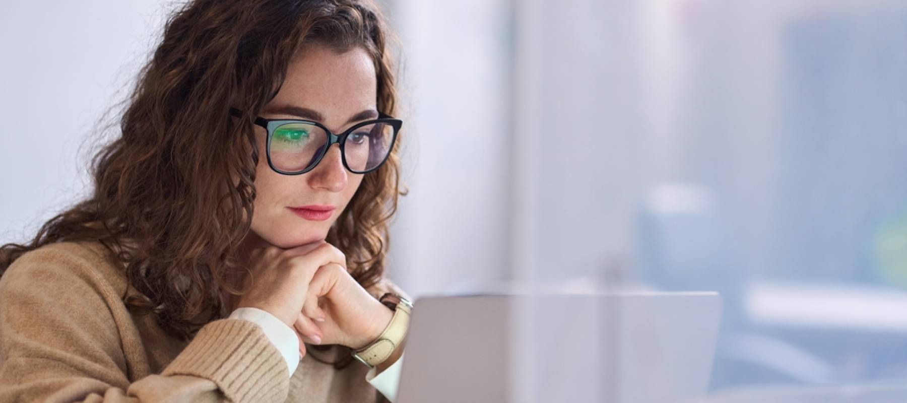 Young thoughtful woman in front of laptop