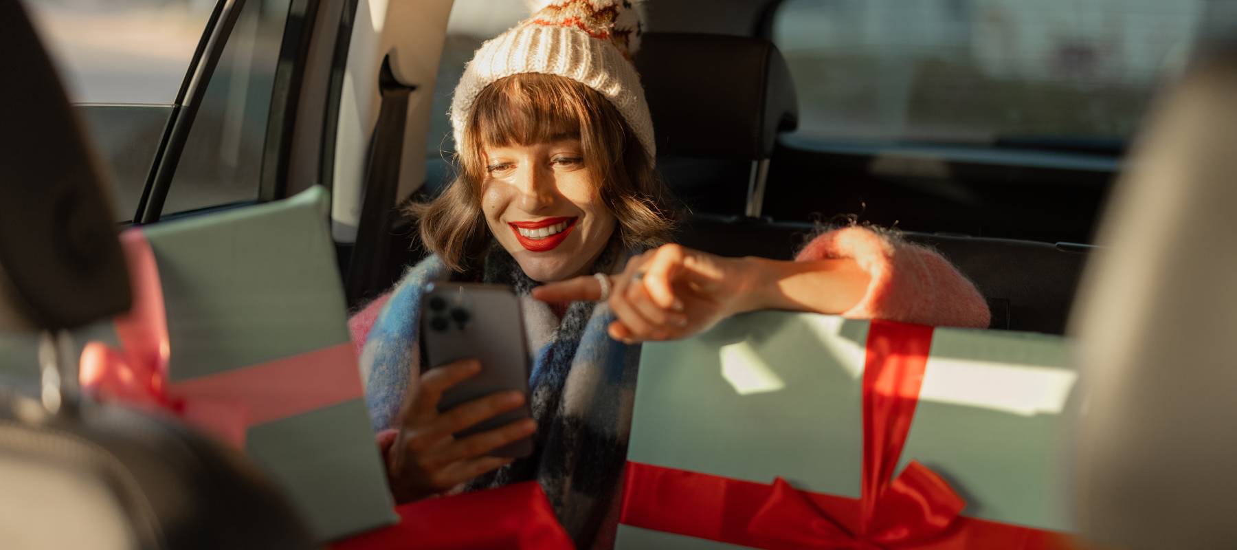 Young woman in back of car with christmas packages