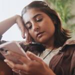 Young woman scrolling through phone on couch