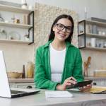 Young woman calculating at kitchen counter