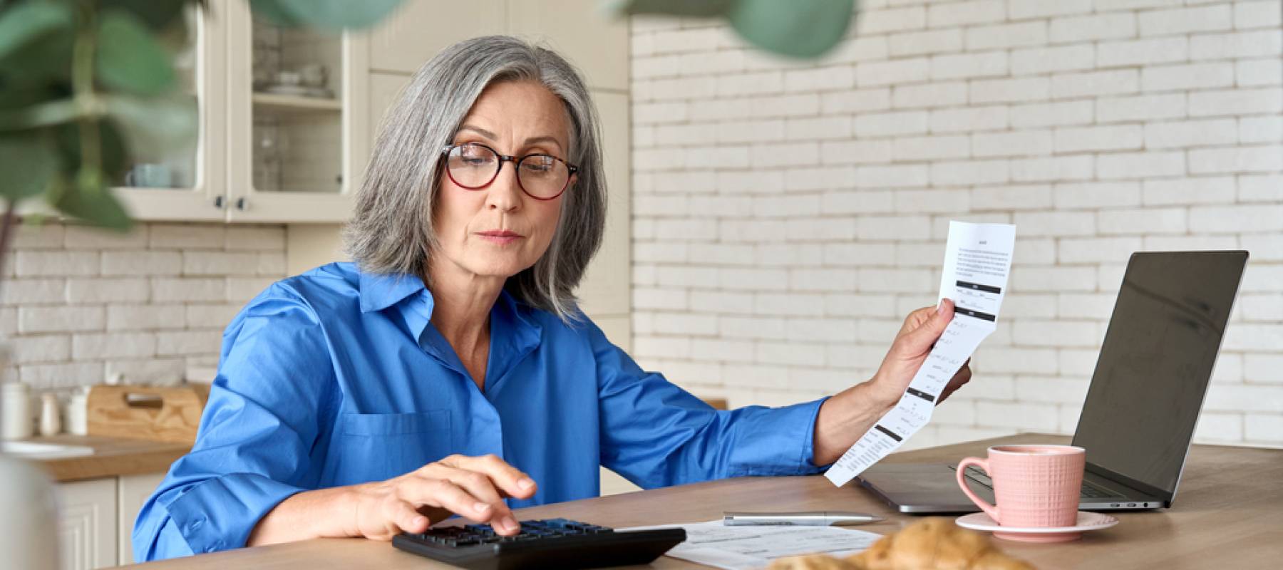 Adult senior 60s woman calculating paper documents at home