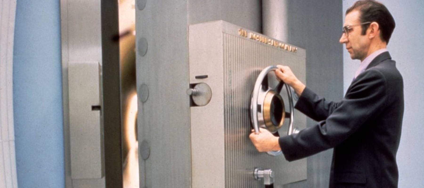 A bank employee closes closes the door of the vault.