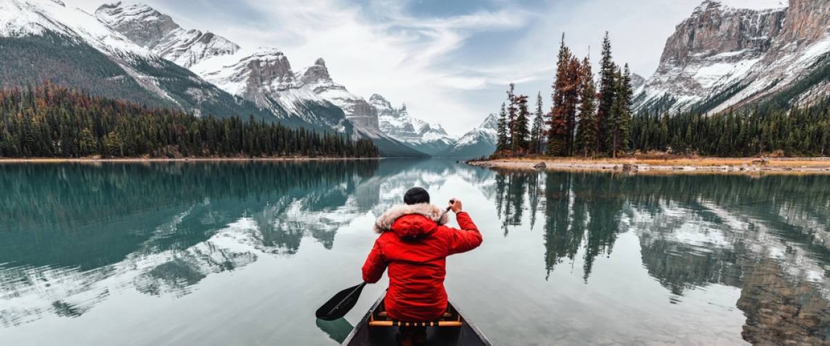 Male traveler in winter coat canoeing in Spirit Island on Maligne Lake at Jasper national park, AB, Canada