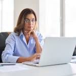 Busy elegant middle aged business woman using laptop working in corporate office